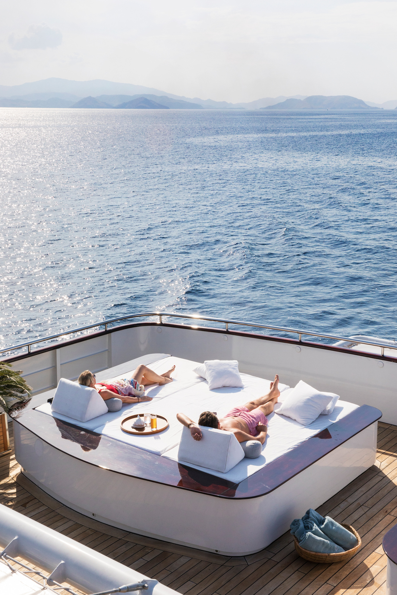 Two guests stretched out on a day bed at the stern, the open sea beyond