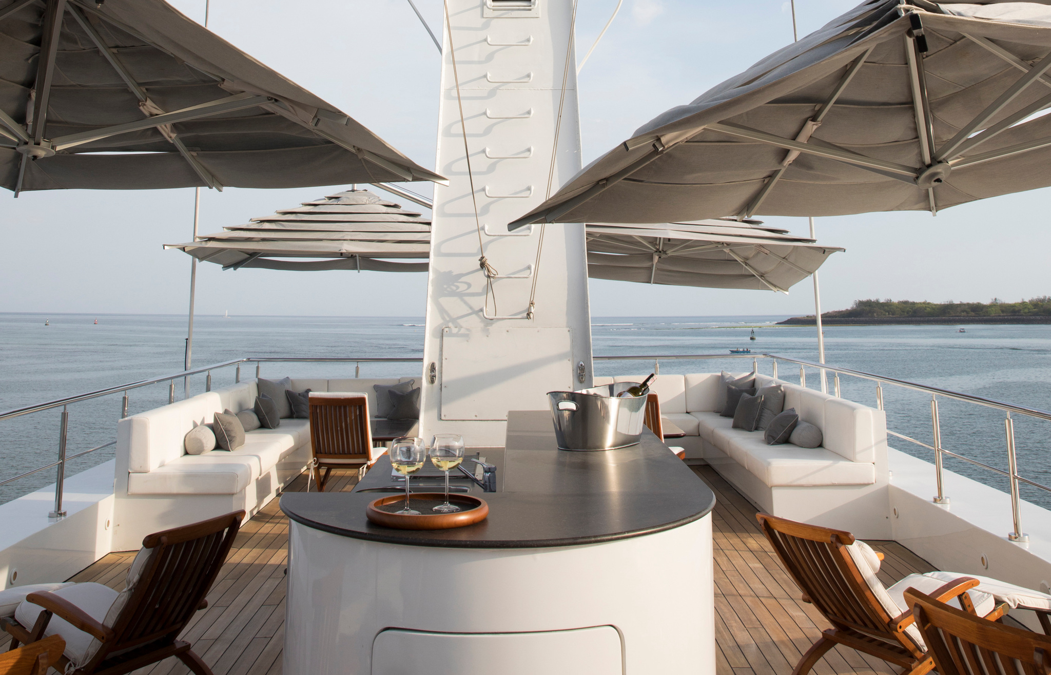 Wraparound sofas, teak chairs and parasols around the mast on the sun deck