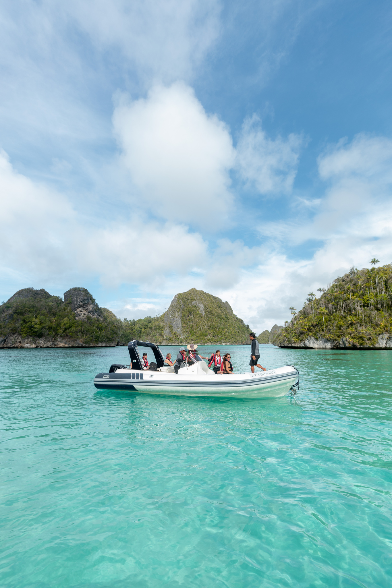 A tender of guests crossing turquoise shallows between forested limestone islands