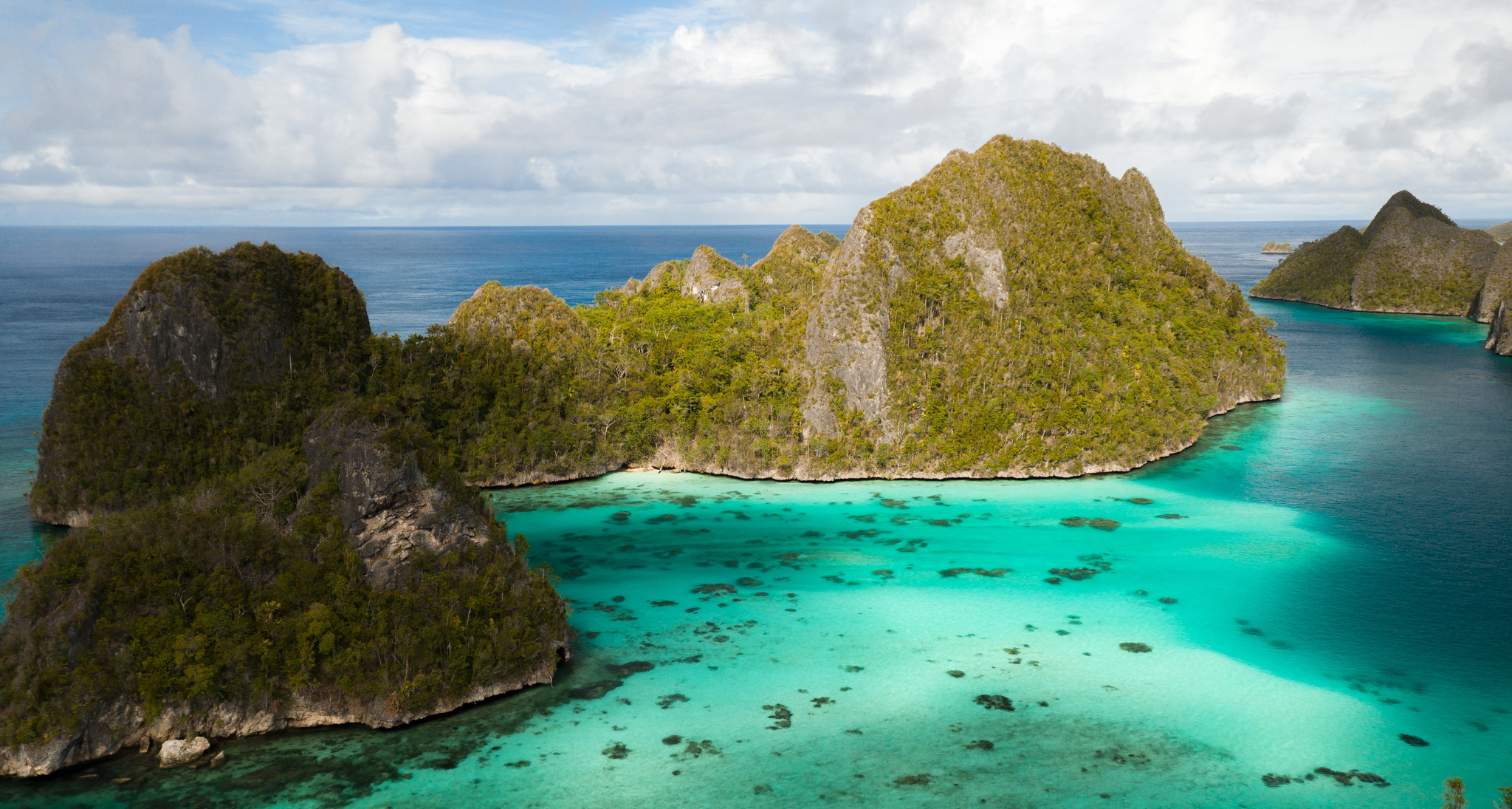 Forested limestone islands rising from a turquoise lagoon at Wayag, from the air